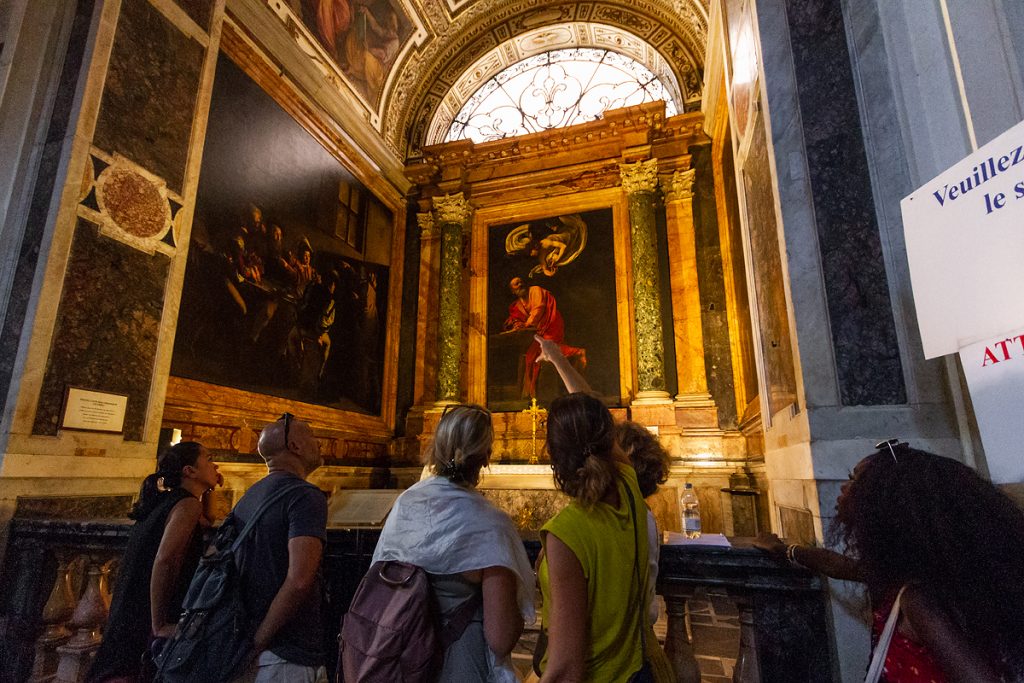 Tour guide explaining Caravaggio inside St Louis of the French