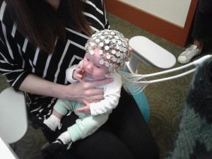Image of a one-month-old infant with an EEG cap. 