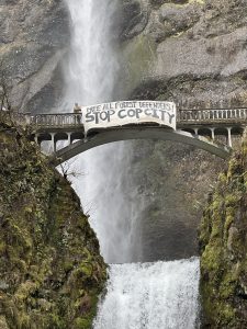 Sign over bridge in Multnomah Falls, OR reads, "Free All Forest defenders! Stop Cop City"