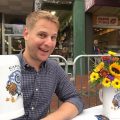Karl Hendler sitting at a bistro table holding a large glass